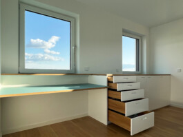 Arbeitsfläche beschichtet mit Linoleum und Unterschränke mit weißen Fronten, Griffräsungen und Schubkästen aus Eiche.