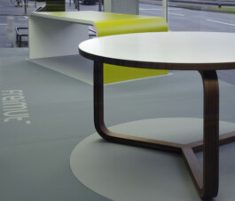 Runder Tisch mit Gestell aus gebogenem Massivholz und beschichteter Tischplatte mit Massivholzkante.