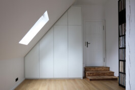 Weißer Einbauschrank mit weißen Fronten unter einer Dachschräge.