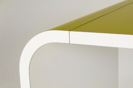 Detailaufnahme einer runden Schreibtisch-Ecke mit HPL beschichtet - Kanten und Unterseite in weiß, Ober- und Außenseite in gelb.