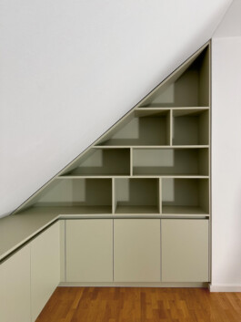 Einbauschrank unter Dachschräge mit offenen und geschlossenen Fächerm in mattem pastell-grün.
