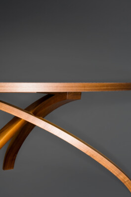 Runder Tisch mit drei gebogenen Beinen aus Massivholz.