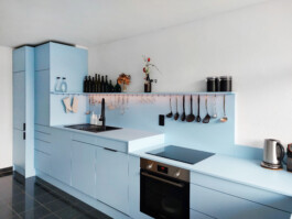 Küche in hellblau, matt, dezente schwarze Griffbleche. 
