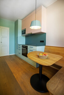 Küchenzeile in türkis und rosa mit einem kleinen Tisch und einer Ecksitzbank aus Eiche. 
