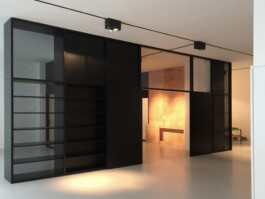 Büroraum aus dunkel gebeizten Elementen, teilweise mit Glas oder mit einem feinem schwarzen Gitter gefüllt. Entwurf Rinnebach Architektur 