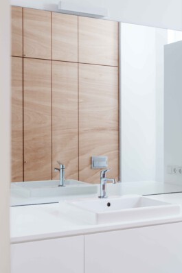 Weißer Waschtisch und Schrank mit Fronten aus Tischlerplatte. 