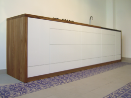 Küche mit weißen Fronten und Arbeitsplatte und Blenden aus Massiolz. 