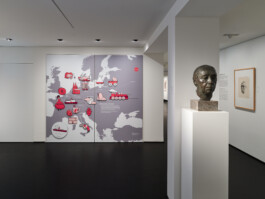 Ausstellungsraum mit einer fast raumhohen Europakarte, auf der mit interaktiven roten Elementen wichtige Stationen im Leben von Käthe Kollwitz gezeigt werden.
