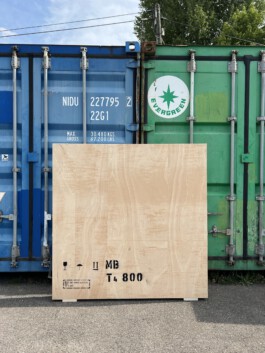 Kiste für den Kunsttransport vor zwei Übersee-Containern 