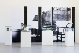 Vier Sockel mit Architektur-Modellen vor einer Wand mit großer Schwarzweiß-Fotografie 