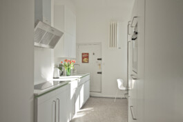 Weiße Küche mit Arbeitsplatte aus Corian und Edelstahlgriffen. 