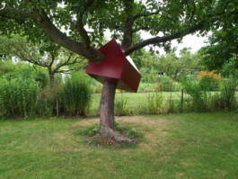 Rote Skulptur in Haus-Form, die um einen Baum gebaut wurde 