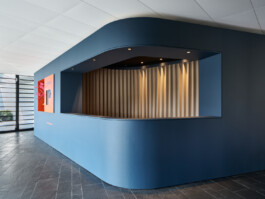 Foyer-Ausbau mit rundem Tresen und Backoffice für die Interprint Group. Die Oberfläche ist beschichtet mit Linoleum in smokey blue. 