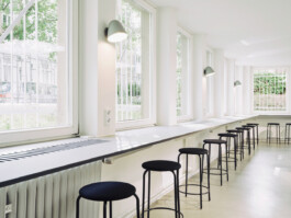 Umlaufende Theke vor Fensternfront aus schwarzem MDF mit hellgrauer super-matter Beschichtung und schwarzen Hockern.