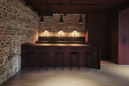 Dunkelrote Küchenzeile mit Barhockern und Leuchten von Nyta.