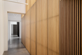 Blick einen Flur entlang mit einer transluzenten Wand aus Lamellen.