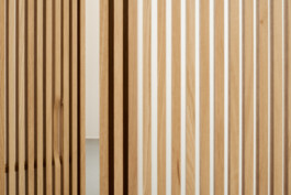 Detailaufnahme der Eiche-Lamellen mit leicht geöffneter Tür und dezenter Grifffräsung.