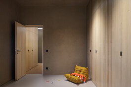 Kinderzimmer mit Lehmputz und raumhohen Einbauschränken aus Dreischichtplatte mit dezenten dunklen Griffen. 