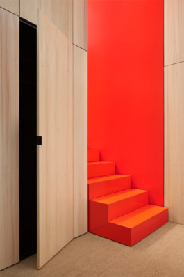 Treppe in Hochglanz-Orange und Wandverkleidung aus Weißtanne. 