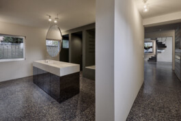 Flur und Badezimmer mit Boden aus Gussterazzo und Waschtisch mit rundem Spiegel. 