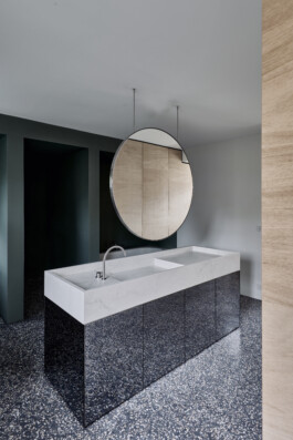 Badezimmer mit frei stehendem Waschtisch mit getönten Spiegelfronten und im Raum hängenden runden Spiegel. 