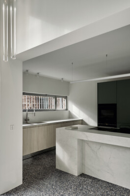 Küchen-Unterschränke mit Fronten aus heller Dreischichtplatte und ein matt-grüner Einbauschrank 