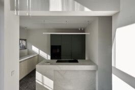 Küchen-Unterschränke mit Fronten aus heller Dreischichtplatte und ein matt-grüner Einbauschrank 