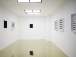 Kleiner weißer Galerieraum mit spiegelndem Boden, an den Wänden 