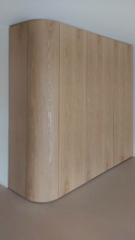 Raumhoher Wohnzimmerschrank mit einer runden Ecke. Die Fronten und Blenden sind Eichefurniert.