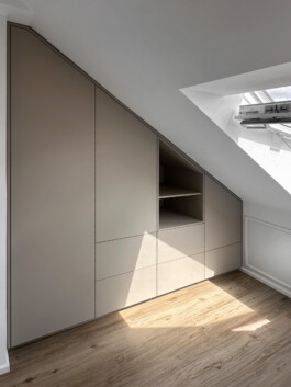 Einbauschrank unter einer Dachschräge mit einem offenen Fach, der Rest geschlossen. Fronten, Blenden und das offene Fach sind aus einer supermatt beschichteten Platte in der Farbe kaschmirgrau.